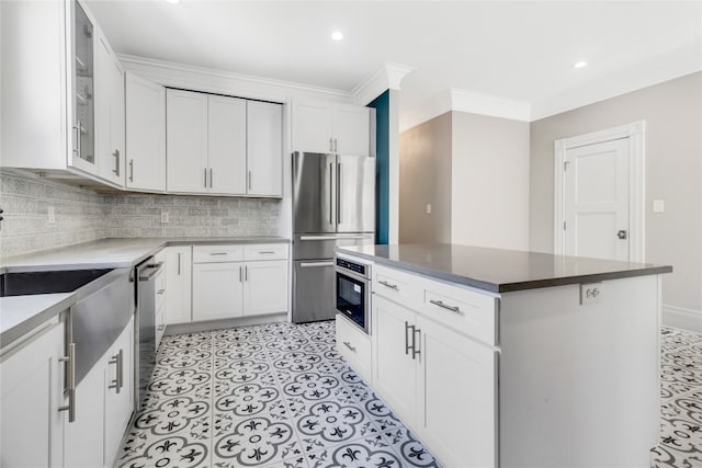 kitchen featuring stainless steel appliances, light tile floors, a kitchen island, white cabinets, and backsplash