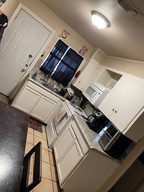 kitchen with light tile patterned flooring, white cabinetry, stone counters, and a textured ceiling