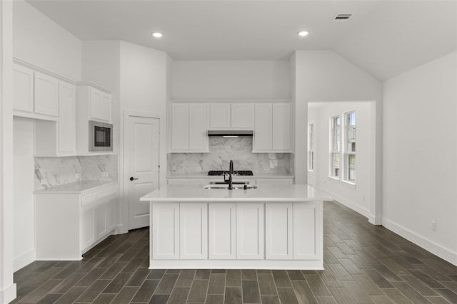 kitchen featuring lofted ceiling, sink, a kitchen island with sink, white cabinetry, and backsplash