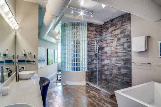 bathroom featuring tile flooring, dual sinks, track lighting, and plus walk in shower