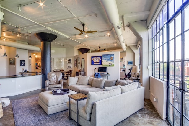 living room featuring ceiling fan, a wood stove, and sink