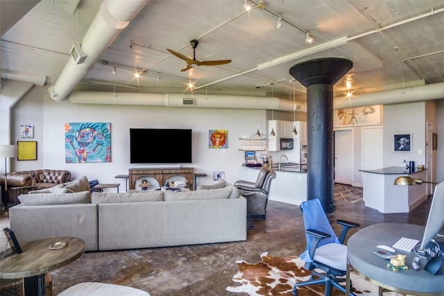 living room with ceiling fan, a wood stove, and sink