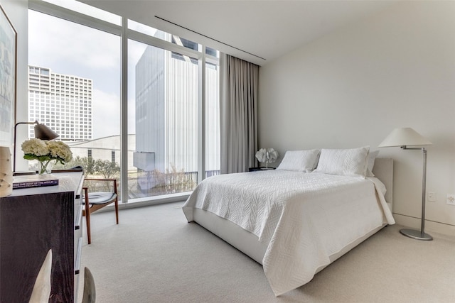 bedroom with light carpet and a wall of windows