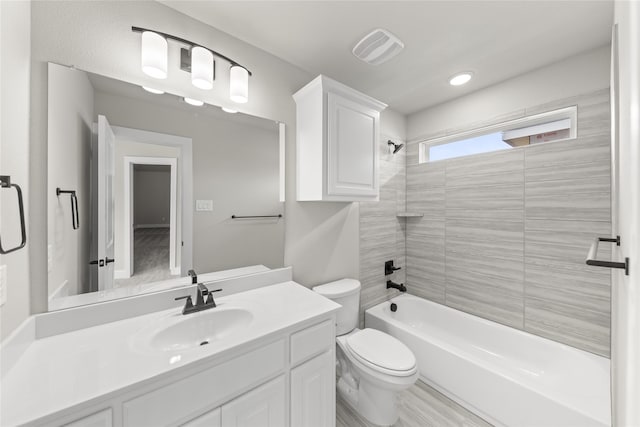 full bathroom featuring tiled shower / bath, vanity, and toilet