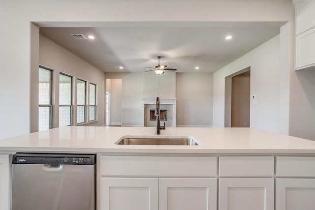 kitchen featuring light countertops, visible vents, stainless steel dishwasher, white cabinets, and a sink