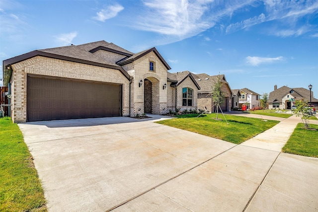 french country inspired facade featuring a garage and a front yard