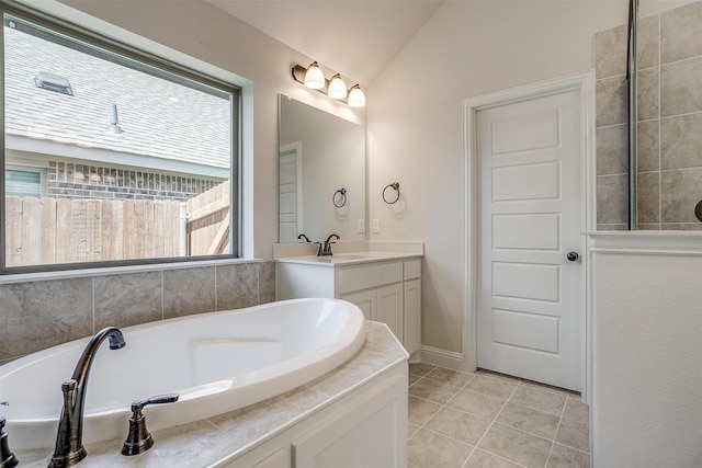 bathroom with a wealth of natural light, lofted ceiling, vanity, and tile patterned flooring