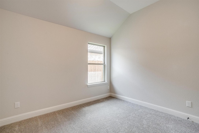 spare room with carpet and vaulted ceiling