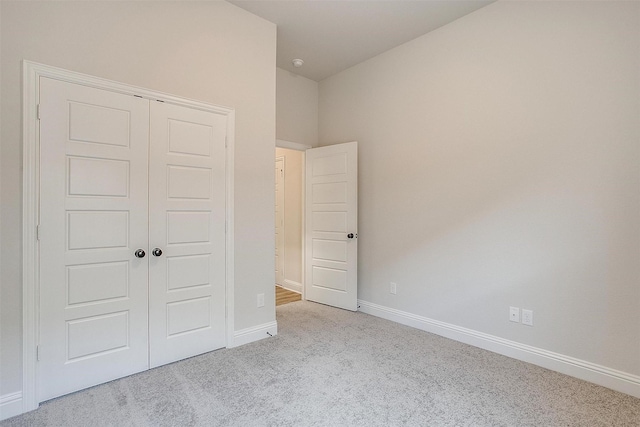 unfurnished bedroom with light carpet, baseboards, and a closet