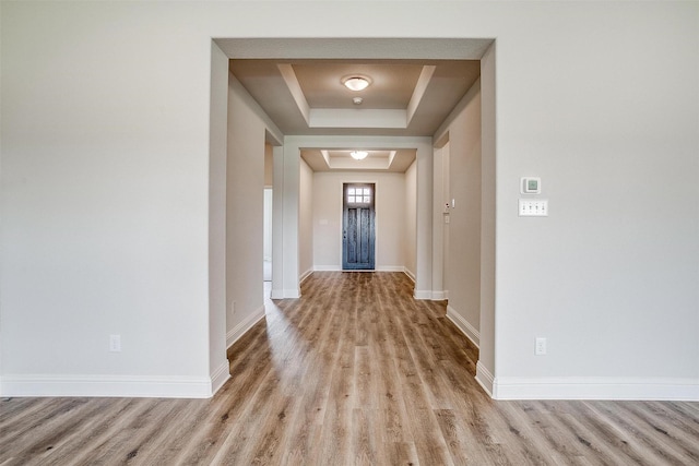 hallway featuring light hardwood / wood-style floors and a raised ceiling