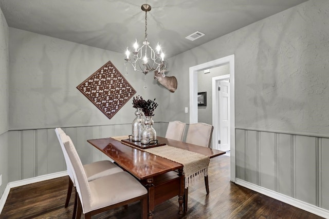 dining space with dark wood-type flooring and a notable chandelier