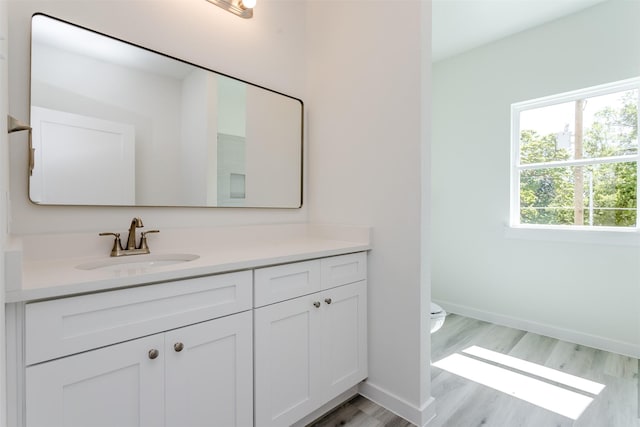 338 N Moore St, Dallas, TX 75203 - bathroom featuring vanity, toilet, wood finished floors, and baseboards