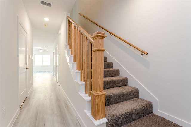 staircase with hardwood / wood-style floors and ceiling fan