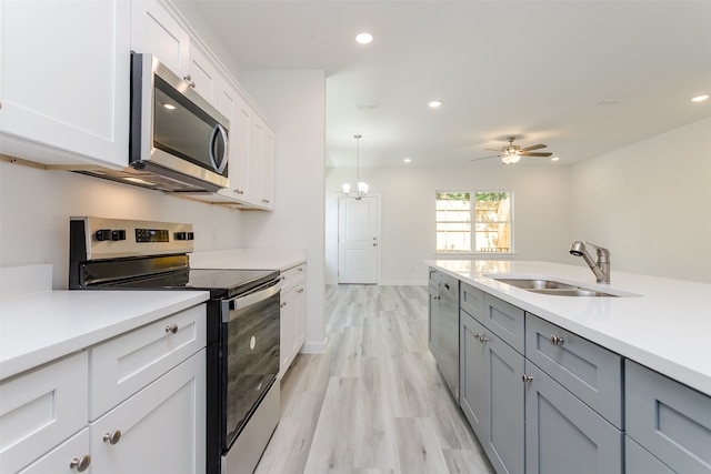 kitchen with white cabinetry, stainless steel appliances, a center island with sink, and light hardwood / wood-style flooring