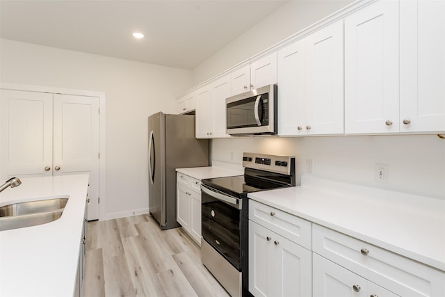 338 N Moore St, Dallas, TX 75203 - kitchen featuring stainless steel appliances, a sink, white cabinets, light countertops, and light wood-style flooring