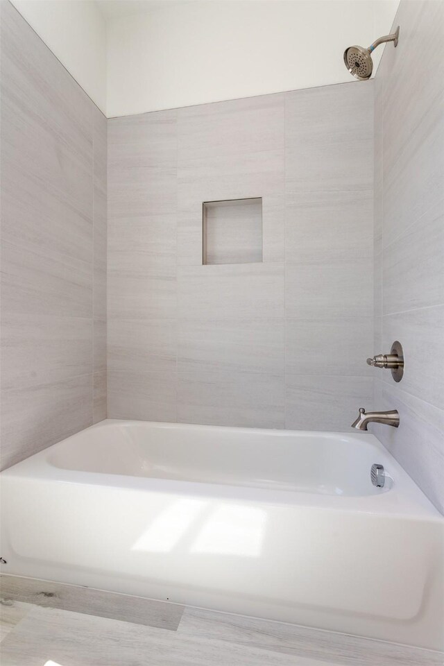 bathroom featuring tiled shower / bath combo and tile walls