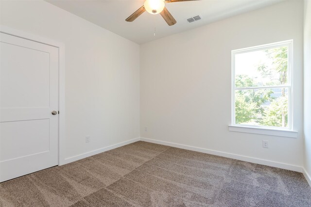 empty room with a wealth of natural light, carpet floors, and ceiling fan