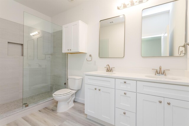 bathroom with hardwood / wood-style floors, vanity, toilet, and a shower with shower door