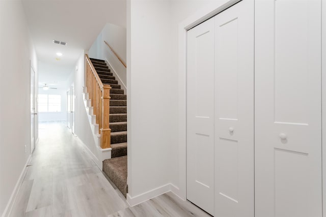 stairs with hardwood / wood-style floors and ceiling fan