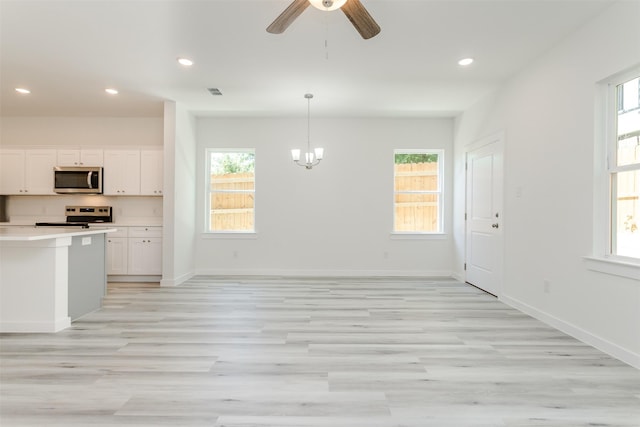 kitchen with a wealth of natural light, light hardwood / wood-style flooring, white cabinets, and stainless steel appliances