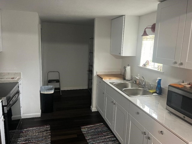 kitchen with dark hardwood / wood-style floors, white cabinetry, range, and sink