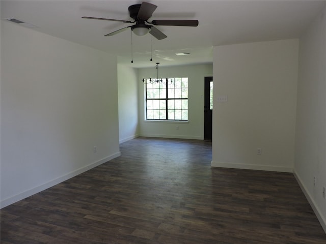 empty room with ceiling fan with notable chandelier and dark wood-type flooring