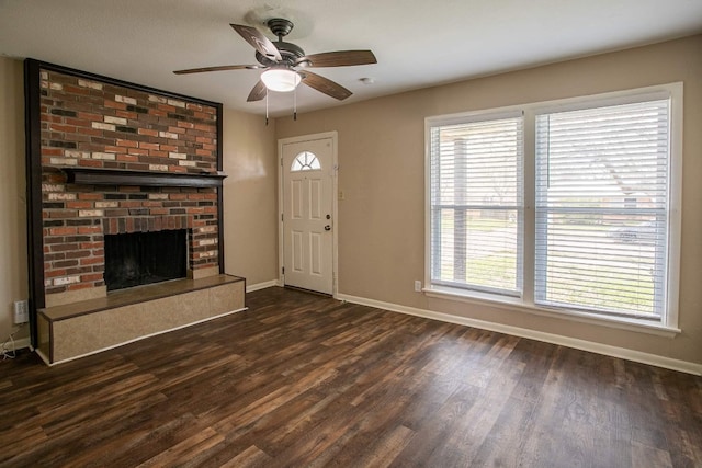 unfurnished living room with plenty of natural light, ceiling fan, dark hardwood / wood-style flooring, and a brick fireplace