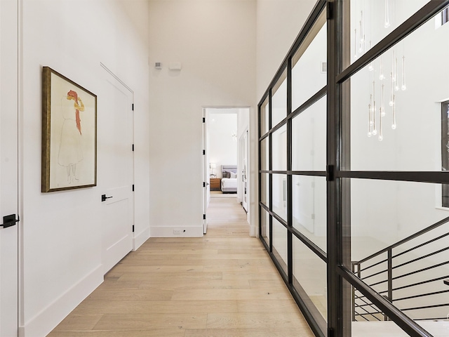 hallway featuring a towering ceiling and light hardwood / wood-style floors