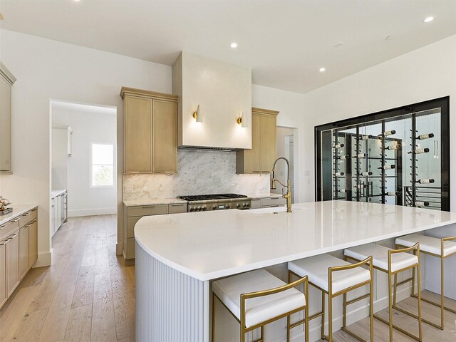 kitchen with a spacious island, light brown cabinetry, light hardwood / wood-style floors, and sink