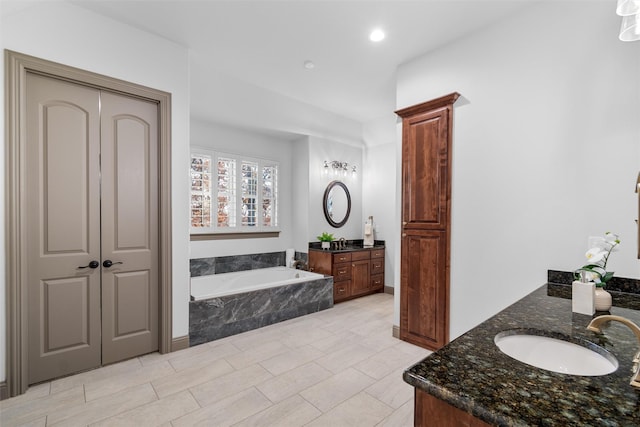 bathroom with tiled tub and vanity