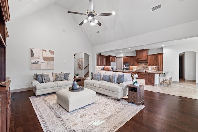 living room featuring dark wood-type flooring, ceiling fan, and high vaulted ceiling