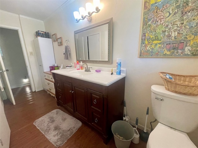 bathroom featuring wood-type flooring, a notable chandelier, toilet, and vanity with extensive cabinet space