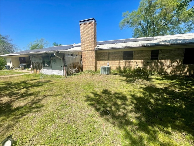 back of house featuring central AC unit and a yard