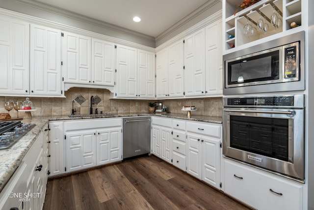 kitchen with light stone countertops, appliances with stainless steel finishes, backsplash, sink, and white cabinetry