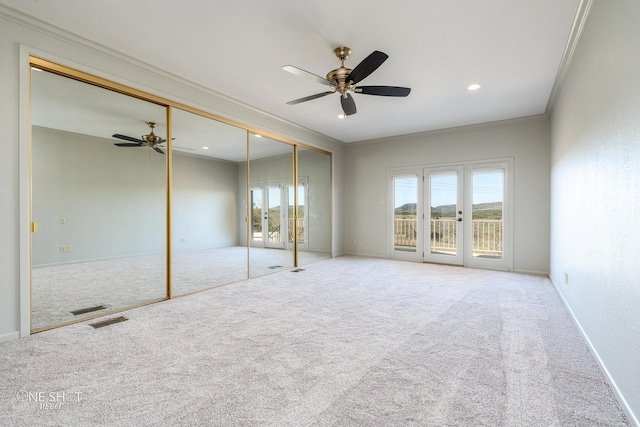 unfurnished bedroom featuring carpet floors, multiple windows, crown molding, and ceiling fan