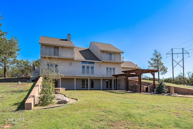 back of house featuring a pergola, a balcony, a yard, and a garage