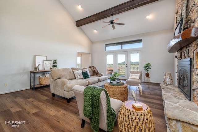 living room with beam ceiling, ceiling fan, a high ceiling, a stone fireplace, and dark hardwood / wood-style flooring