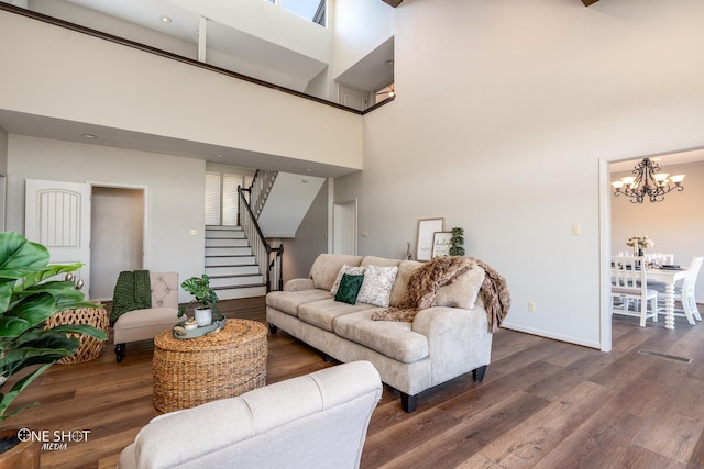 living room with a high ceiling, dark hardwood / wood-style floors, and a notable chandelier