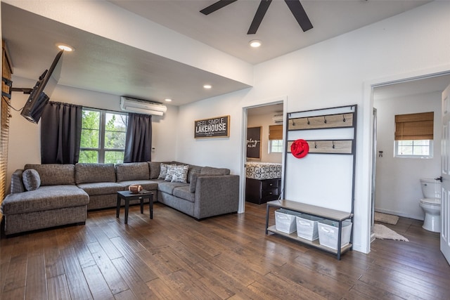 living room featuring a wall mounted air conditioner, dark hardwood / wood-style flooring, and ceiling fan