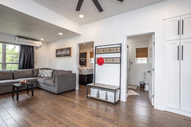 living room featuring a wall mounted air conditioner, ceiling fan, and dark hardwood / wood-style flooring