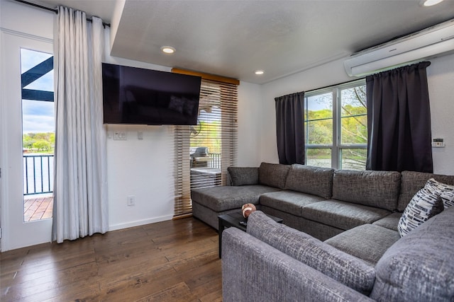 living room with an AC wall unit, dark hardwood / wood-style floors, and a wealth of natural light