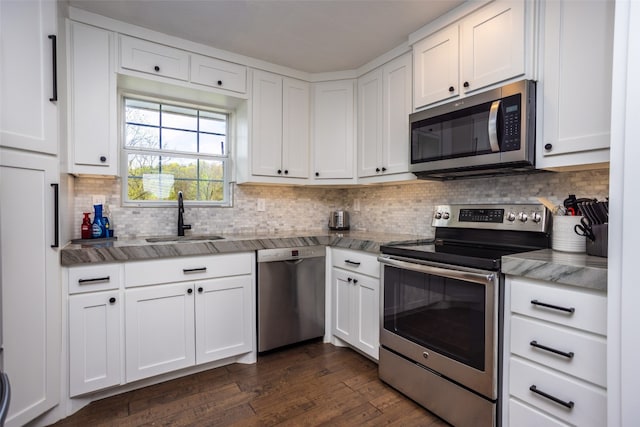 kitchen with sink, stainless steel appliances, dark wood-type flooring, tasteful backsplash, and white cabinetry