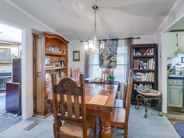 dining area featuring an inviting chandelier, a textured ceiling, crown molding, and light colored carpet