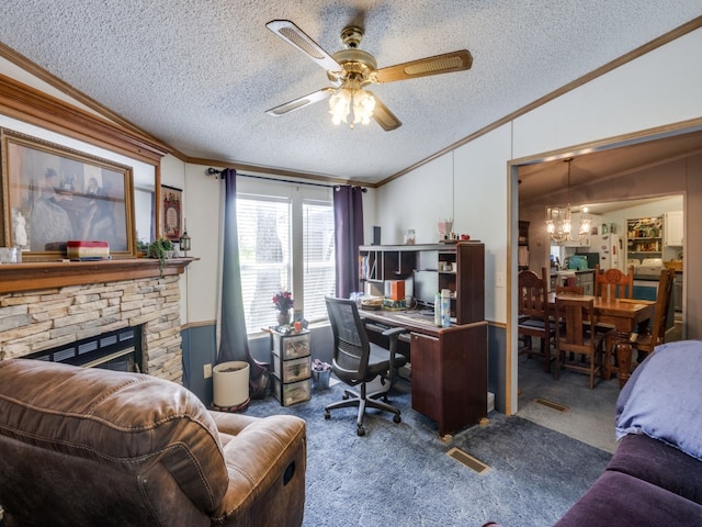 carpeted home office with ornamental molding, vaulted ceiling, a textured ceiling, ceiling fan with notable chandelier, and a stone fireplace