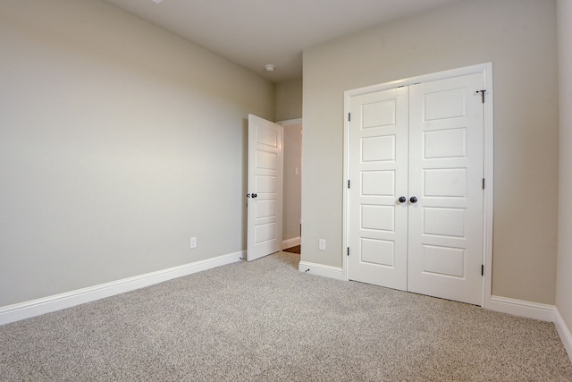 unfurnished bedroom featuring light carpet and a closet