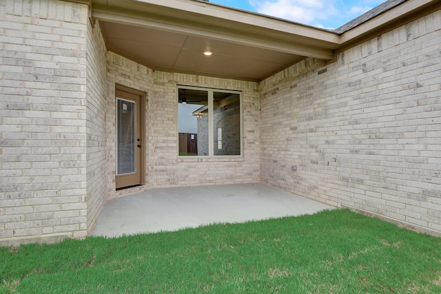 view of exterior entry featuring a lawn and a patio area