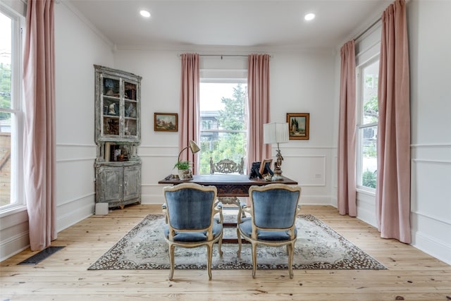 dining space with ornamental molding, plenty of natural light, and light hardwood / wood-style flooring