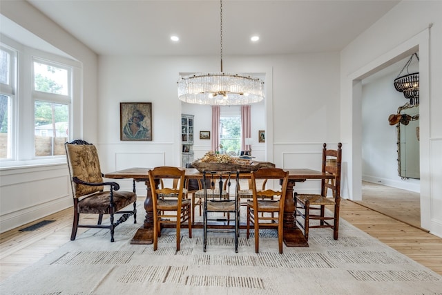 dining area featuring light hardwood / wood-style flooring, a wealth of natural light, and a chandelier