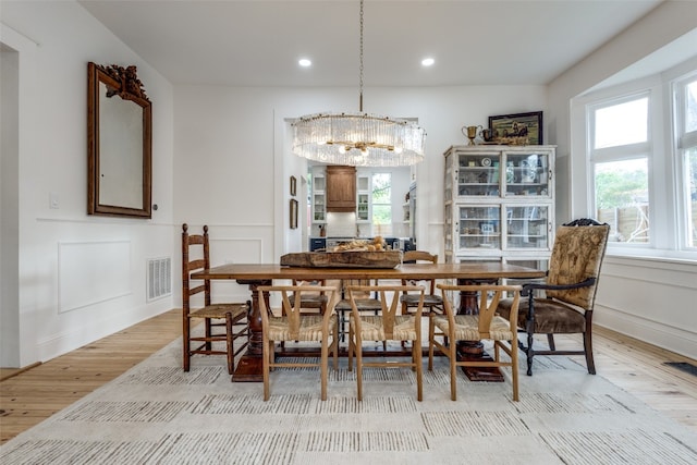 dining space with light hardwood / wood-style flooring, a healthy amount of sunlight, and a chandelier