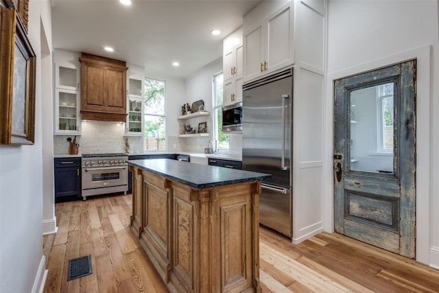 kitchen with a kitchen island, high end appliances, light hardwood / wood-style flooring, and backsplash